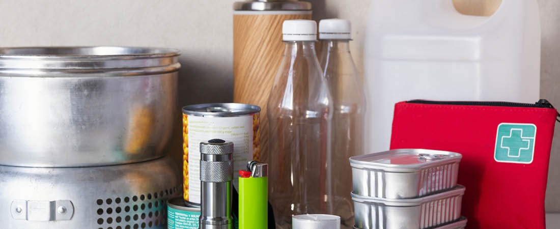 Flaskor, stomkök, första hjälpen, vatten dunk, ljus och en tändare står på ett bord