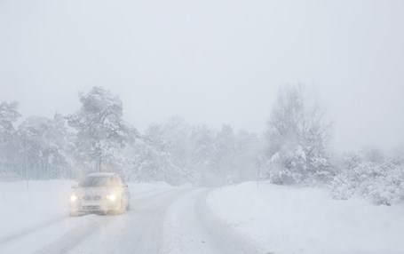 Bil kör i snöstorm.