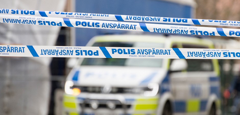 Polisavspärrning med vitblå band. i bakgrunden syns en polisbil.