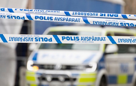 Polisavspärrning med vitblå band. i bakgrunden syns en polisbil.