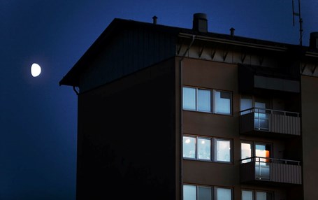 Höghus med fönster och balkonger. Mörk himmel i bakgrunden.