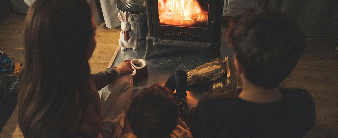 Tre barn sitter framför en kamin. 