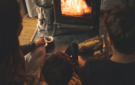 Tre barn sitter framför en kamin. 