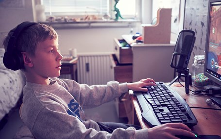 Pojke sitter framför dator.