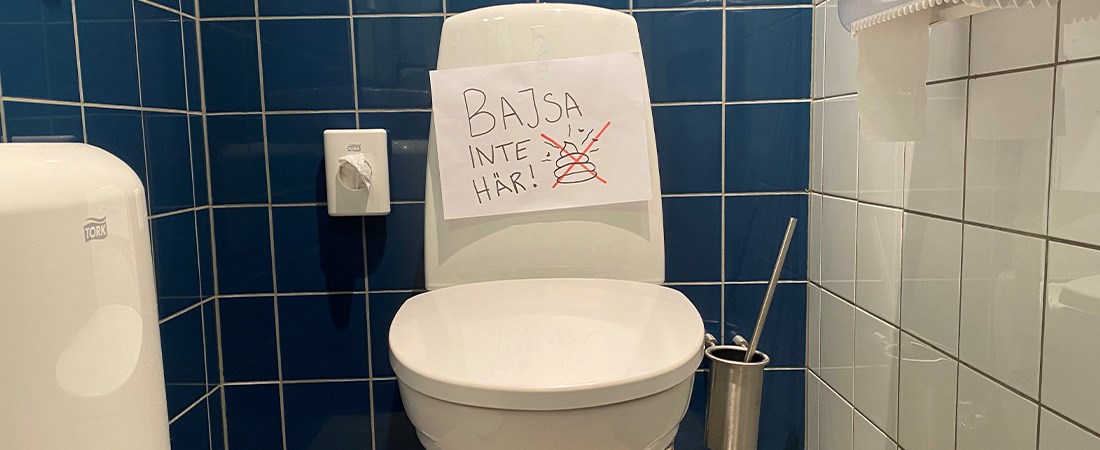 Toalett med en handskriven skylt där det står "Bajsa inte här". 