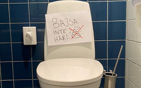 Toalett med en handskriven skylt där det står "Bajsa inte här". 