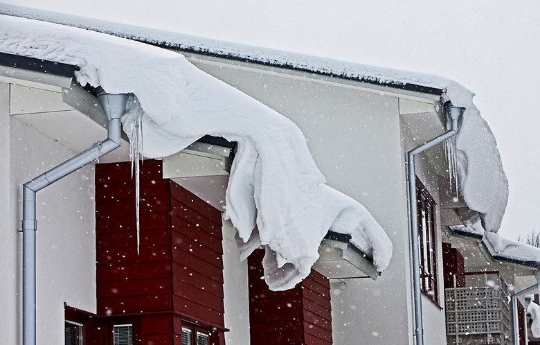 Snö och istappar hänger från ett tak.