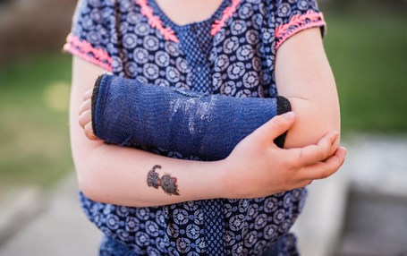Flicka med bandagerad arm. 