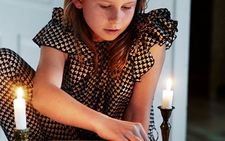 Flicka som spelar spel i ljuset från stearinljus