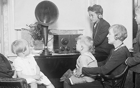 Svartvid bild av stor familj som lyssnar på radion tillsammans, tidigt 1900-tal