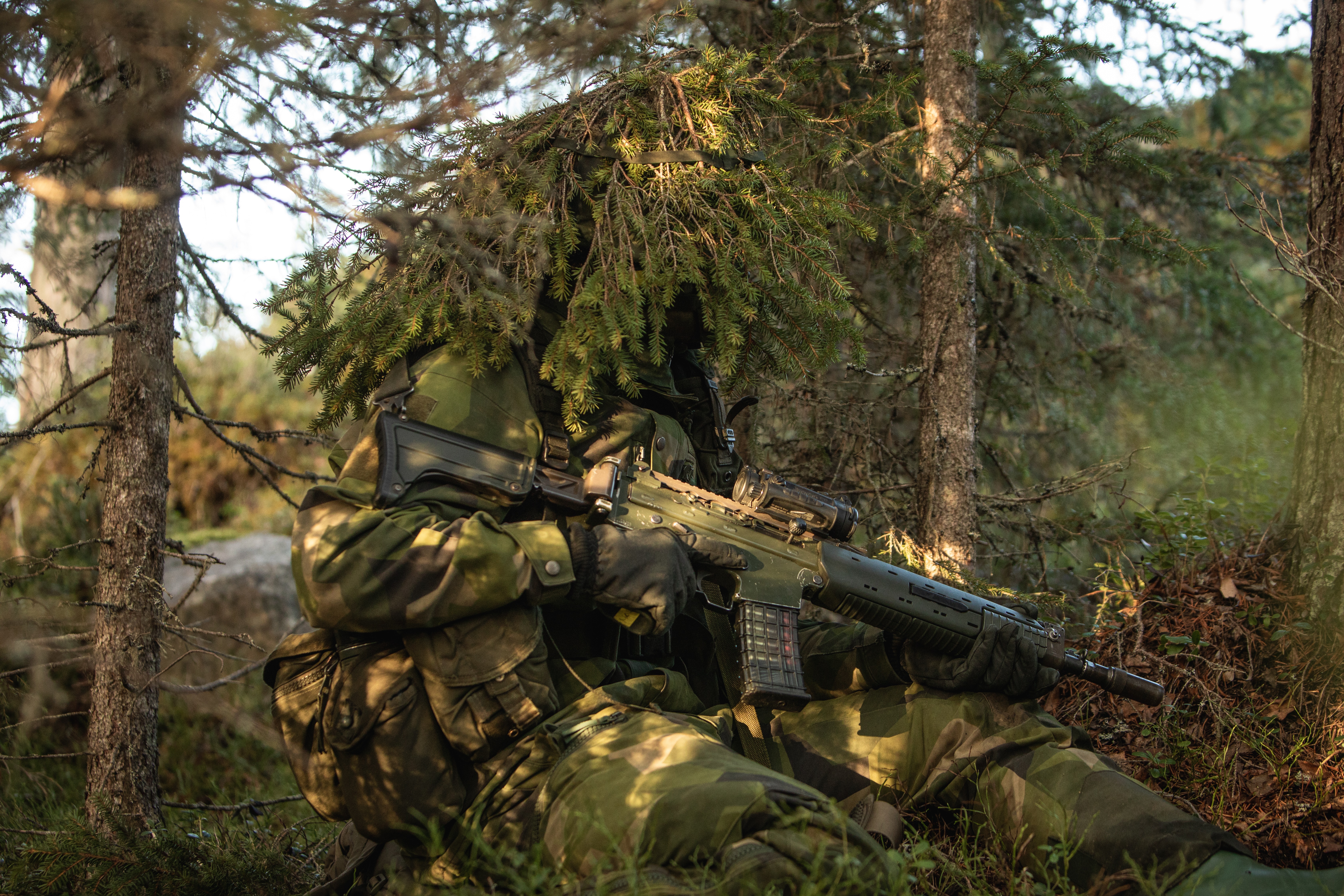 Kamouflerad jägarsoldat i skogen. 