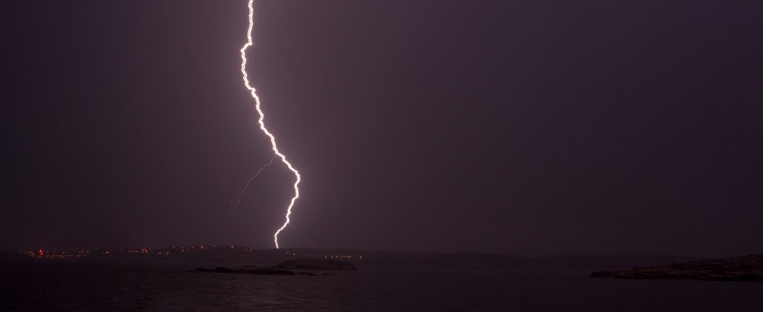 Blixt slår ner över en mörk himmel och en upplyst sta